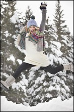 USA, Utah, Salt Lake City, portrait of young woman in winter clothing leaping. Photo : Mike Kemp