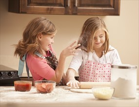 Two girls (10-11) preparing pizza in kitchen. Photo : Mike Kemp