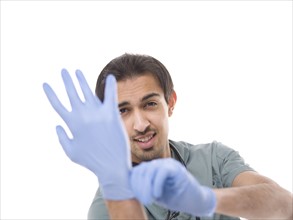 Young surgeon putting on protective gloves. Photo : Dan Bannister