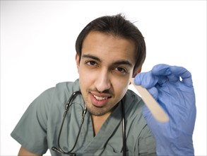 Young surgeon holding wooden stick for examining patients throat . Photo : Dan Bannister