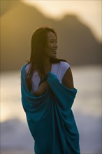 USA, California, San Francisco, Young woman wrapped in blanket at coast. Photo : Noah Clayton