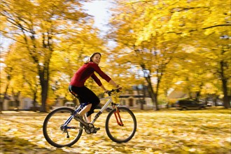 USA, Montana, Kalispell, Young woman cycling in park. Photo : Noah Clayton