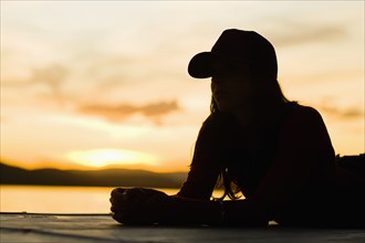 USA, California, Silhouette of young woman relaxing on beach at sunset. Photo : Noah Clayton