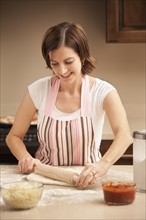 Woman preparing pizza dough in kitchen. Photo : Mike Kemp