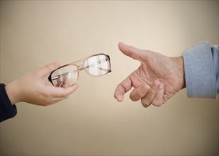 Close up of hands of grandfather and grandson (8-9) with glasses. Photo : Jamie Grill Photography
