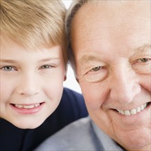 Close up of smiling faces of grandfather and grandson (8-9) . Photo : Jamie Grill Photography