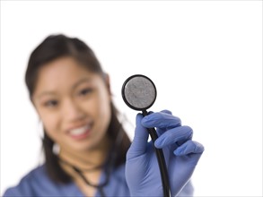 Young cheerful female surgeon holding stethoscope. Photo : Dan Bannister