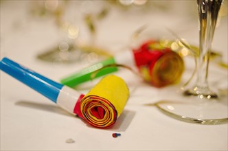 Party horn blower and champagne flute on table, close-up.