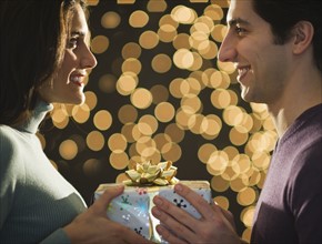 Young couple giving Christmas presents each other. Photo : Daniel Grill