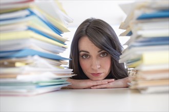 Young woman looking at stack of documents at desk.