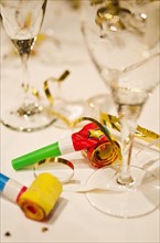 Party horn blowers and champagne flutes on table, close-up.
