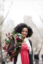 USA, Washington State, Seattle, Cheerful young woman holding christmas wreath. Photo : Take A Pix