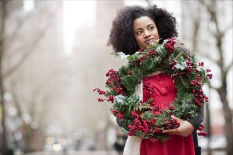 USA, Washington State, Seattle, Young woman holding christmas wreath. Photo : Take A Pix Media