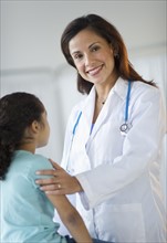 Female pediatrician examining girl (6-7) in doctor's office.