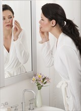 Woman removing make-up in bathroom.