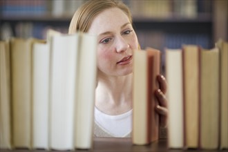Woman looking for book in library.