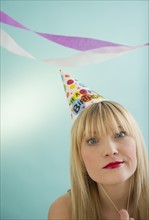 Young woman wearing party hat smirking. Photo: Jamie Grill Photography