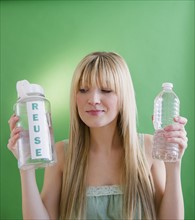 Young woman holding plastic bottles. Photo : Jamie Grill Photography