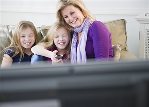 Mother and daughters (8-11) watching tv. Photo: Jamie Grill Photography