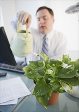 Businessman watering plant. Photo : Jamie Grill Photography