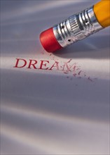 Studio shot of pencil erasing the word dream from piece of paper. Photo : Daniel Grill