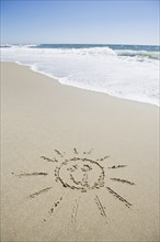 USA, Massachusetts, Sun face drawn on sandy beach. Photo : Chris Hackett