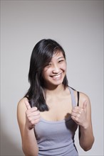 Portrait of cheerful young woman with thumbs up. Photo : Winslow Productions