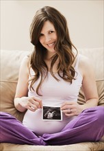 Young pregnant woman holding CT image of unborn baby. Photo: Mike Kemp