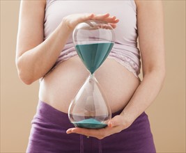 Young pregnant woman holding hourglass. Photo: Mike Kemp