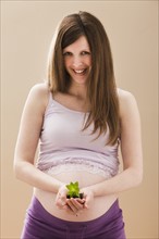 Young pregnant woman holding young plant. Photo: Mike Kemp