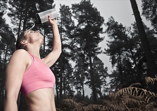 England, Suffolk, Female athlete pouring water on head, Thetford Forest. Photo : Justin Paget
