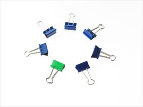 Blue and green bulldog clips on white background. Photo : David Arky