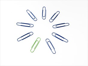 Blue and green paper clips on white background. Photo: David Arky