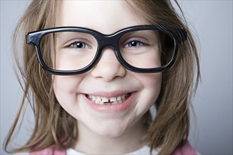 Studio portrait of girl (6-7) wearing big glasses. Photo: Justin Paget