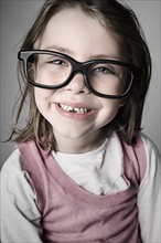 Studio portrait of girl (6-7) wearing big glasses. Photo : Justin Paget