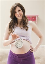 Young pregnant woman holding alarm clock. Photo: Mike Kemp