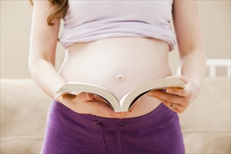 Young pregnant woman holding open book. Photo: Mike Kemp