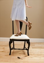 Young woman standing on chair, evading mouse. Photo: Mike Kemp