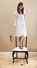 Young woman standing on chair, evading mouse. Photo: Mike Kemp