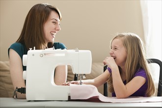 Girl (8-9) and young woman using sewing machine. Photo : Mike Kemp