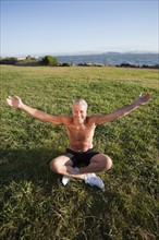 USA, California, Berkeley, Senior man sitting cross-legged on grass. Photo : Noah Clayton