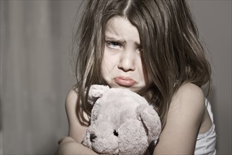 Studio portrait of sad girl (6-7) with pink teddy bear. Photo: Justin Paget