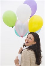 Young woman holding bunch of balloons laughing.