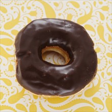 Studio shot of chocolate donut on floral background.
