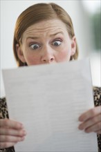 Woman reading document looking surprised.