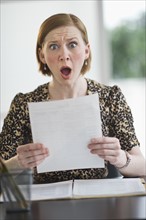Woman reading document looking surprised.