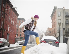 USA, New Jersey, Jersey City, woman jumping on snow by street. Photo: Jamie Grill Photography