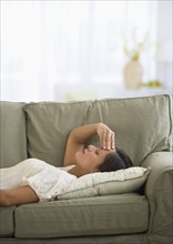 Woman lying on sofa with headache.