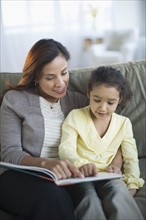 Mother reading book with daughter (6-7).