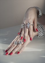 Close up of woman's hands with red nail polish and diamond jewelry.